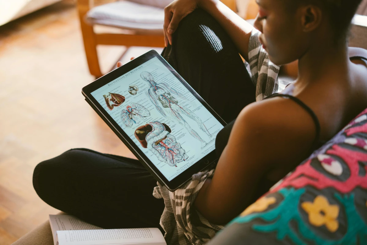 Estudiante de medicina organizando su material de estudio en un escritorio con libros, un cuaderno y un laptop.